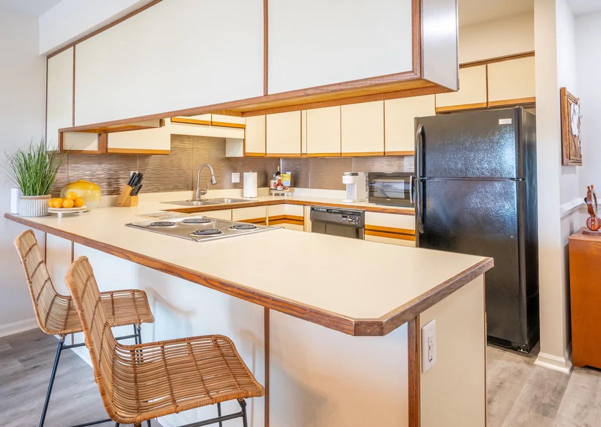 This image showcases a kitchen island with bar stools and modern appliances, offering a casual seating option for informal breakfasts or engaging chats while meals are prepared. The layout encourages interaction and togetherness, ideal for both meal prep and socializing.