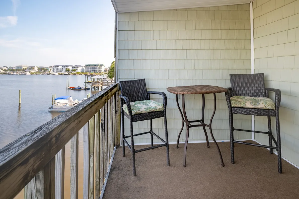 A private balcony featuring cushioned seating with a serene view of the water. The tranquil setting showcases a peaceful moment perfect for morning coffee or evening relaxation while watching boats pass by and the sun set over the marshland.