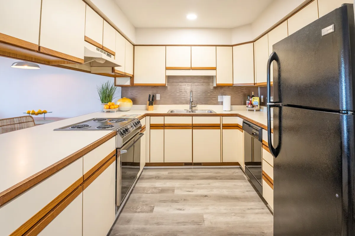 This image captures a welcoming kitchen scene featuring stainless steel appliances, wooden cabinetry, and a countertop adorned with fresh fruits. The space radiates warmth, suggesting the environment is perfect for cooking and gathering, with hints of ongoing meal preparation or family activity.